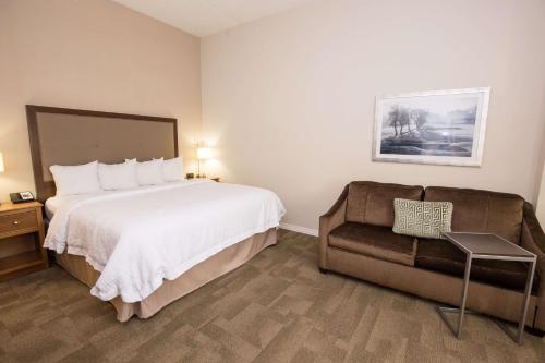 a hotel room with a bed and a couch at Hampton Inn & Suites - Pittsburgh/Harmarville, PA in Harmarville