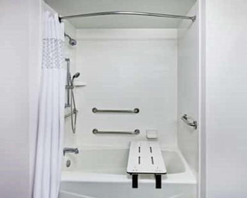 a white bathroom with a bath tub and a bench at Hampton Inn By Hilton Bulverde Texas Hill Country in Bulverde