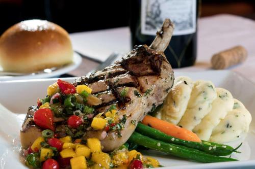 a plate of food with meat and vegetables and a bottle of wine at DoubleTree by Hilton Hotel Miami Airport & Convention Center in Miami
