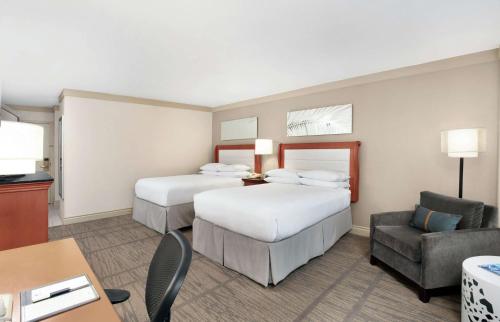a hotel room with two beds and a chair at DoubleTree by Hilton Hotel Miami Airport & Convention Center in Miami