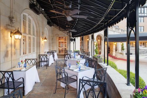 un restaurante con mesas blancas y sillas en un patio en Hotel Roanoke & Conference Center, Curio Collection by Hilton en Roanoke