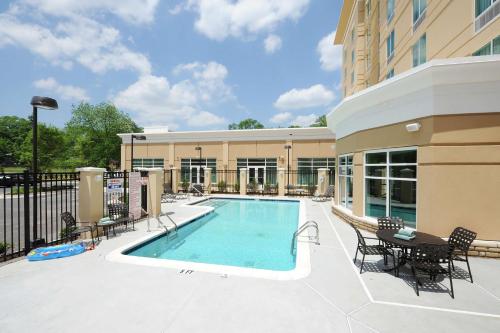 亞特蘭大的住宿－亞特蘭大機場北希爾頓花園酒店，一座带椅子和桌子的游泳池位于一座建筑旁边