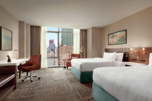 a hotel room with two beds and a desk at Hilton Garden Inn Chicago Downtown South Loop in Chicago