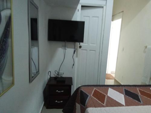 um quarto com uma cama e uma televisão na parede em Hostal María Fernanda em Santo Domingo