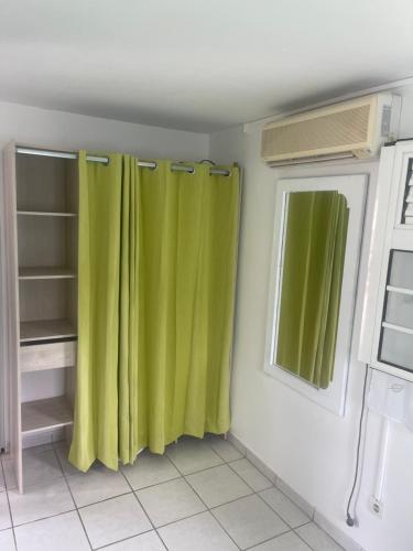 una cocina con cortinas verdes en una habitación en La rose, en Le Robert