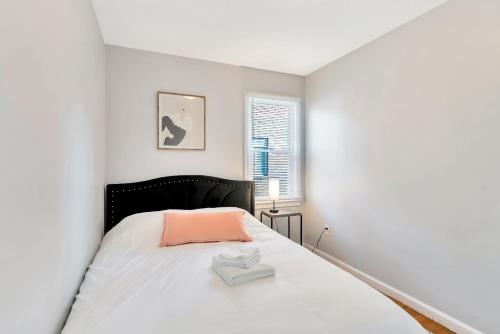 Dormitorio blanco con cama con almohada rosa en Comfortable Family Residence near Downtown Detroit, en Detroit
