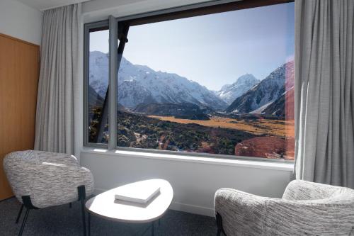 a room with a large window with a view of mountains at The Hermitage Hotel Mt Cook in Mount Cook Village