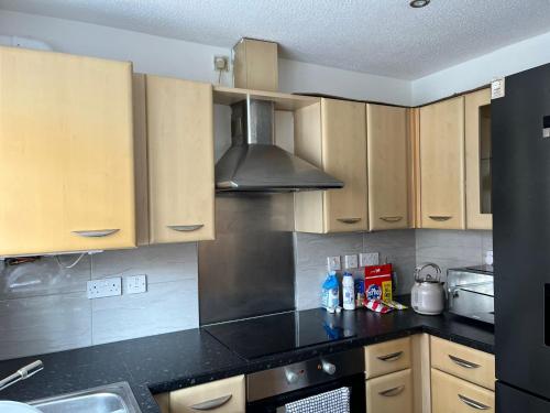 a kitchen with wooden cabinets and a black counter top at Cozy house with free parking in Manchester