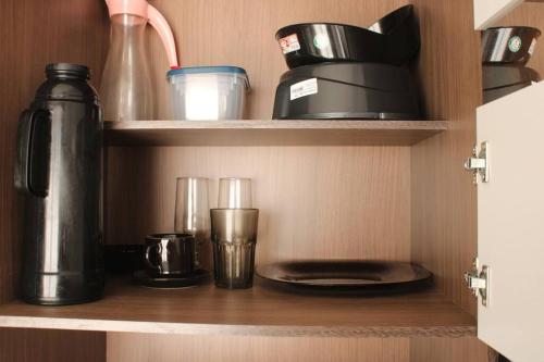 a cupboard with a coffee pot and glasses on it at Casa 02 Quartos Condomínio Aceita Pet in Ourinhos