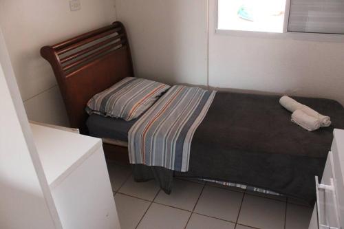 Dormitorio pequeño con cama con manta a rayas en Casa 02 Quartos Condomínio Aceita Pet en Ourinhos