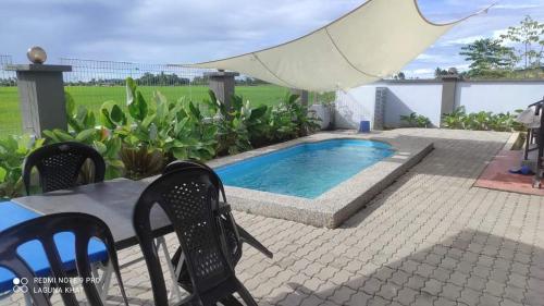 a swimming pool in a patio with a table and chairs at Murni Inn Kampung Perigi in Yan