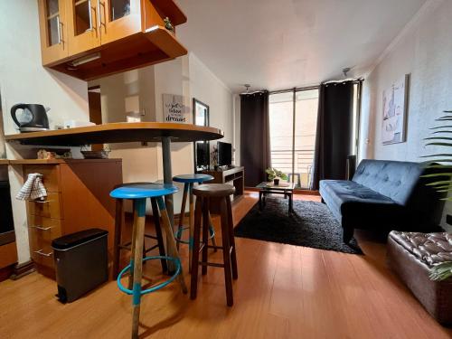 a living room with a couch and a bar with stools at Apartamentos City Centro Los Leones in Santiago
