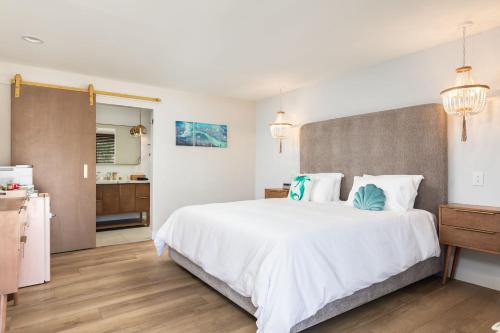 a bedroom with a large white bed and a bathroom at California Inn in Anaheim