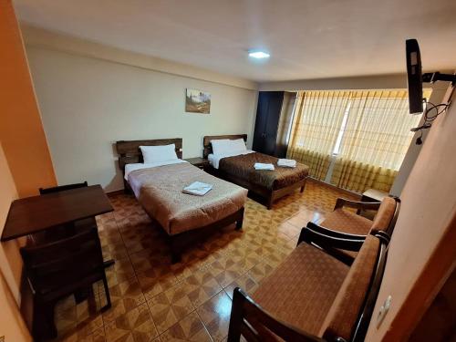 Habitación de hotel con 2 camas y escritorio en Chaska valle Inn, en Urubamba