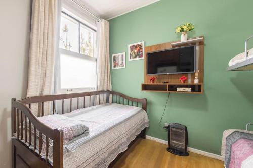a bedroom with a crib and a tv on a green wall at Apto perto de Itaipava in Petrópolis