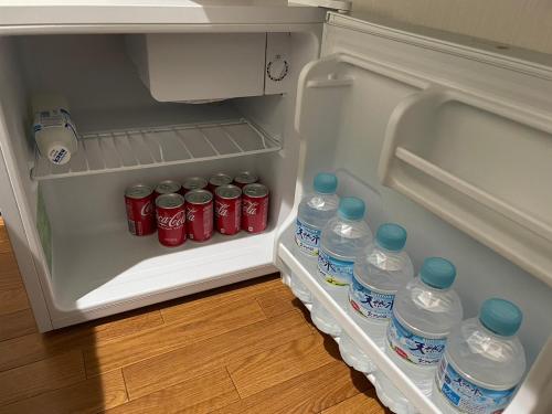 an open refrigerator filled with bottles of water at 民泊くるり in Nagoya