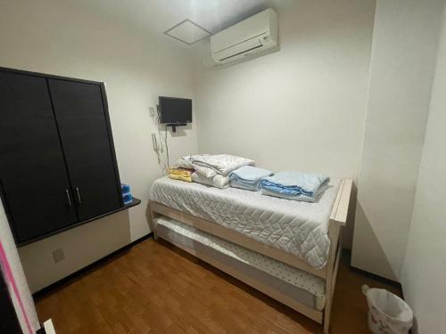 Kleines Zimmer mit einem Bett und einem TV in der Unterkunft 民泊くるり in Nagoya