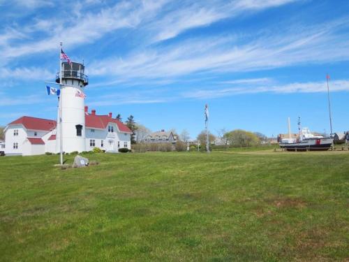 a lighthouse on a grass field with a boat in front at 14 Hallet Lane Chatham Cape Cod - - Sand Simeon in Chatham