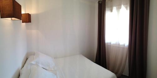 a bedroom with a white bed and a window at Le Diodon De Sagone in Sagone