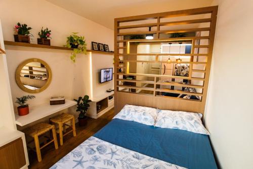een kleine slaapkamer met een bed en een spiegel bij Areia Preta Park Studio | Salma Haddad in Guarapari