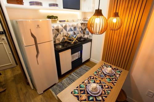 a small kitchen with a refrigerator and a table at Areia Preta Park Studio | Salma Haddad in Guarapari