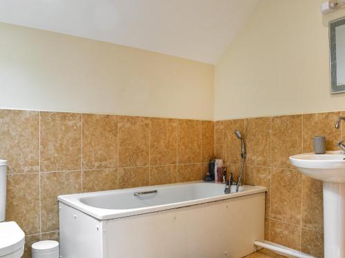 a bathroom with a tub and a sink at Llandremor Fawr Cottage in Llanedy
