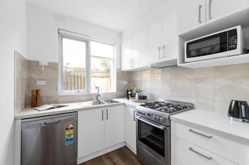 a kitchen with white cabinets and a stove and microwave at Serene Coastal Haven in Melbourne