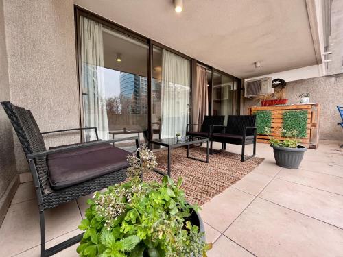 a living room with a couch and chairs and plants at Apartamentos City Centro Los Leones in Santiago