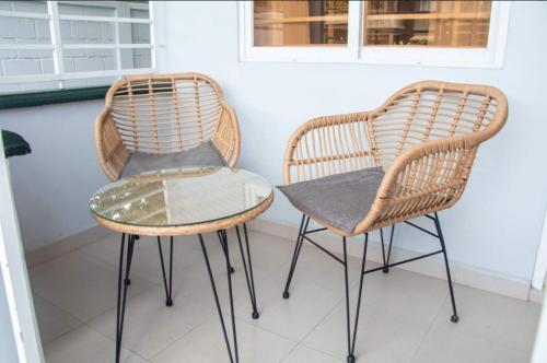 2 sillas de mimbre, mesa de cristal y silla en R&R Apartments en Paramaribo