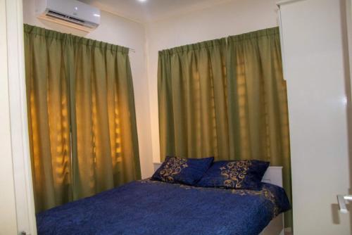 1 dormitorio con 1 cama con sábanas azules y cortinas verdes en R&R Apartments en Paramaribo