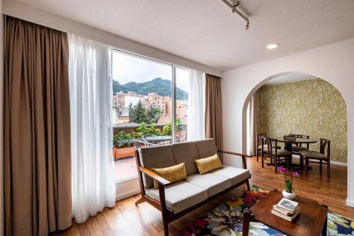 a living room with a couch and a large window at Hotel Vilar América in Bogotá
