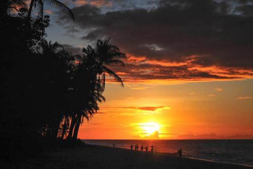 a sunset on a beach with palm trees and the ocean at Boracay Sea View Hotel in Boracay