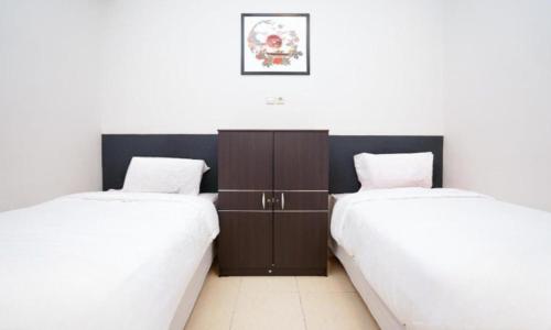 a bedroom with two beds and a cabinet between them at Semampir Residence By Occupied in Surabaya