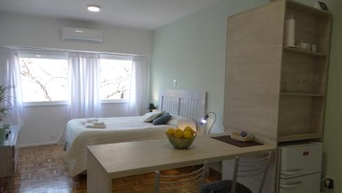 Adrogué的住宿－Monoambiente en pleno centro de Adrogué，一间卧室配有一张床和一张桌子及一碗水果