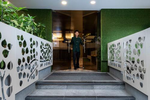 a man walking down a hallway with a green wall at Hotel Vilar América in Bogotá