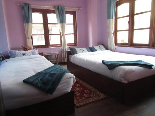 two beds in a room with purple walls and windows at STUPA VIEW INN in Kathmandu