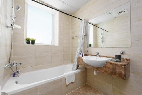 a bathroom with a tub and a sink and a mirror at Maison Privee - Lovely Apt with Lake Walkways Close to JBR Beach in Dubai