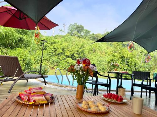 une table avec des assiettes de nourriture sur une table avec des parapluies dans l'établissement Caofong Glamping Village Hoà Bình, à Hòa Bình