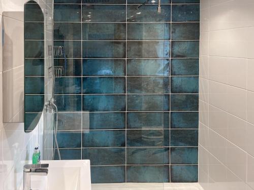 La salle de bains est pourvue d'une douche avec du carrelage bleu. dans l'établissement Afallon, à Conwy