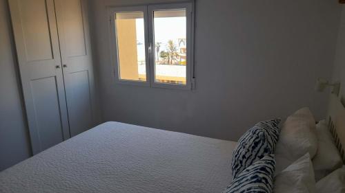 a white bedroom with a bed and a window at playa las americas a 50 metros playa las vistas apartamento torres del sol in Playa de las Americas