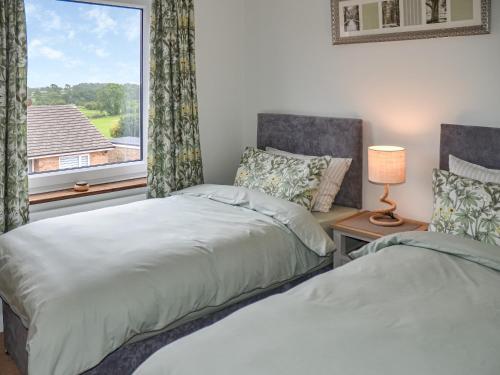 2 camas en una habitación con ventana en Rivendell en Burgh by Sands