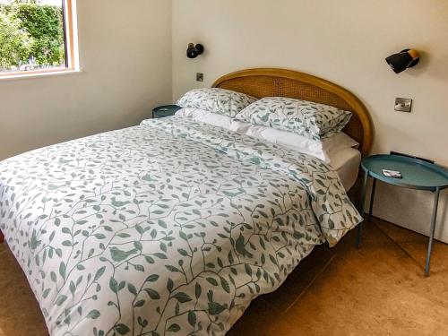 a bedroom with a bed with a green and white comforter at Wrens Nest in Chippenham