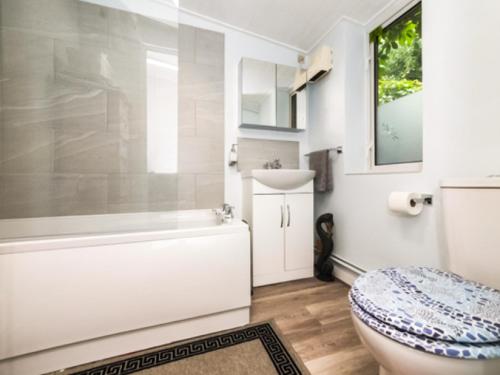 a bathroom with a tub and a toilet and a sink at Burwood Cottage in Rotherfield Peppard