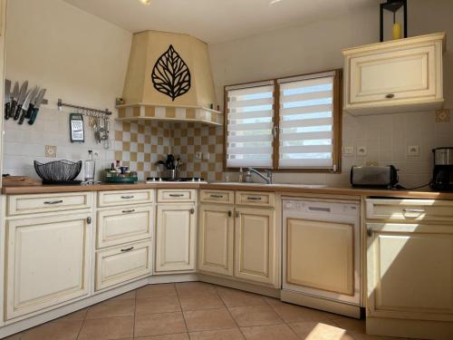 une cuisine avec des armoires blanches et un sol carrelé dans l'établissement Maison traditionnelle au calme, 3 chambres, jardin, proche des commerces et de la Ria d'Etel - FR-1-397-74, à Locoal-Mendon