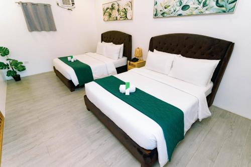 a bedroom with two beds with green and white sheets at 3 Peaks Resort & Boutique Hotel in Lipa