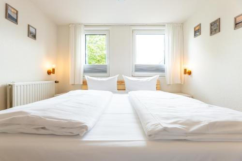 a large white bed in a room with windows at Appartement EBB in Morsum