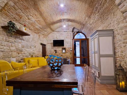 sala de estar con mesa de madera y pared de piedra en O rosa bella, en Gubbio