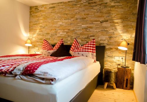 ザウテンスにあるFerienhaus Ötztal-Lodgeのベッドルーム1室(赤と白の枕が備わるベッド1台付)