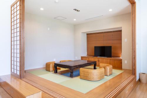 a living room with a table and chairs and a tv at AOI Sauna SPA & Dog Villa HAKODATE in Hakodate