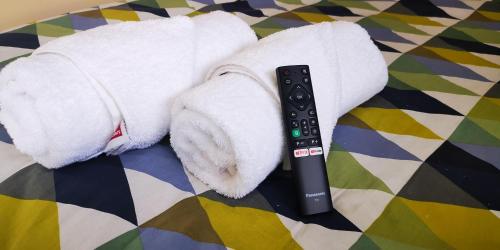 a remote control sitting next to a stack of towels at Stay Hostel Rotorua in Rotorua